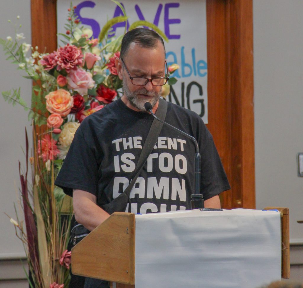 Jeff looks down at his notes while speaking at a podium