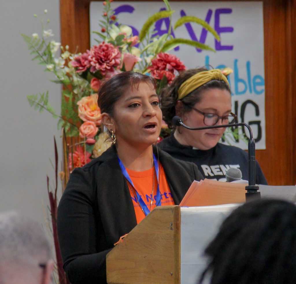 Gris speaking at a podium, Lindsey a little bit over her shoulder