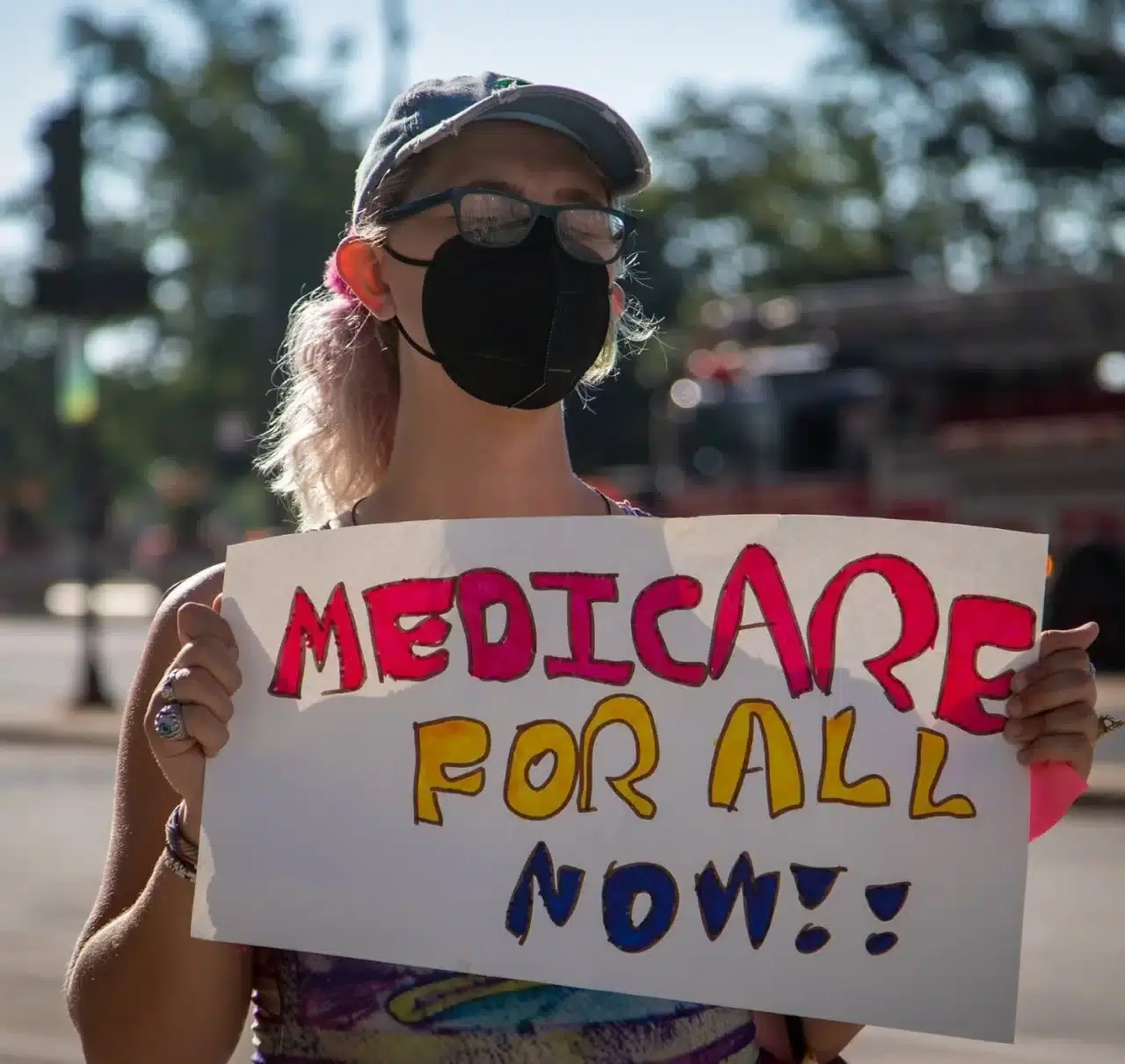 Person Holding Medicare For All Now Sign 1280x1211